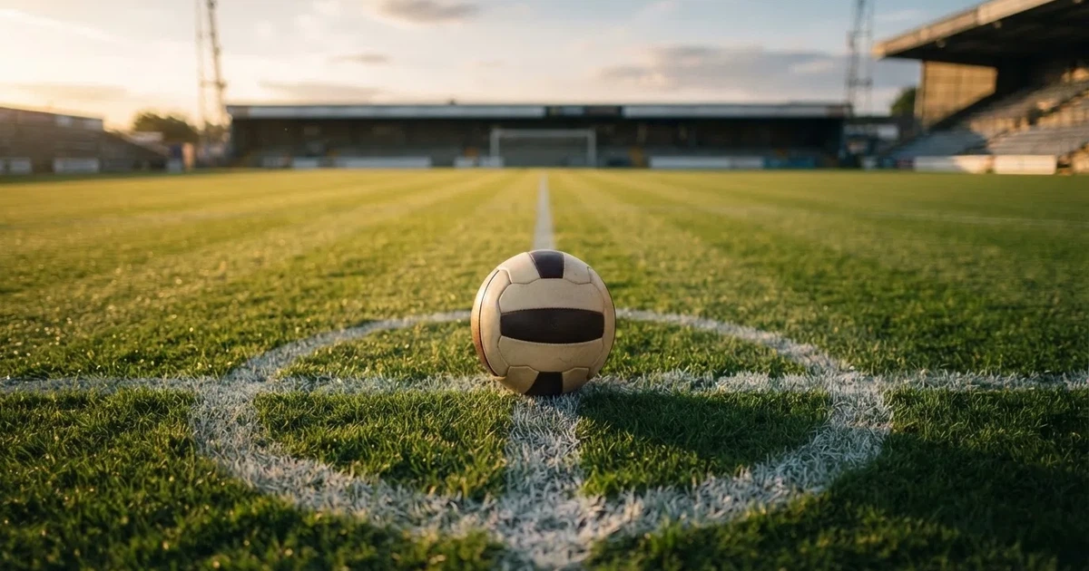 Ein Fussball liegt auf dem Mittelkreis eines Rasenfelds, die weissen Linien kreuzen sich auf dem gepflegten Gras im warmen Abendlicht.