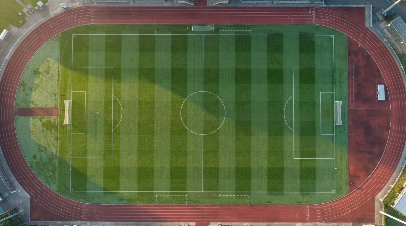 Ein Fussballplatz von oben gesehen, die Linien bilden ein helles Muster auf dem Rasen, Drohnenperspektive in der Morgendämmerung.
