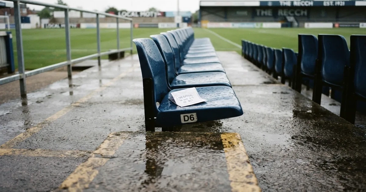 Eine Reihe leerer Sitzschalen auf der Tribüne eines kleinen Stadions, auf den Stufen glänzt Regenwasser.