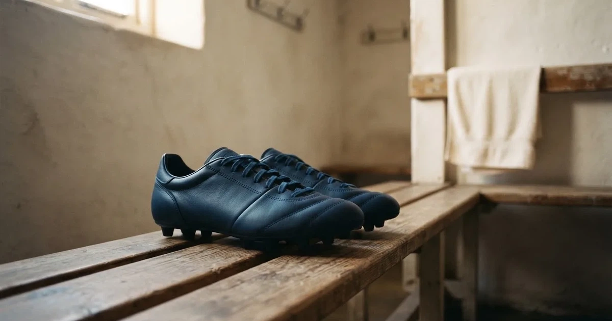Zwei Fussballschuhe stehen nebeneinander auf einer Holzbank in einer leeren Umkleidekabine.